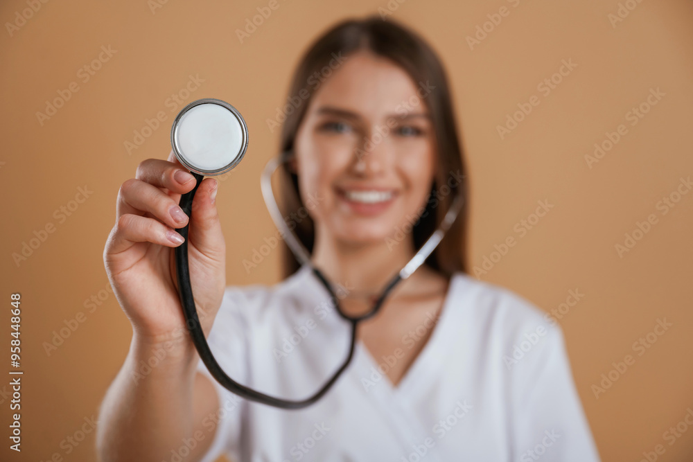 Stethoscope in hand. Young pretty woman is against background in the studio Stethoscope in hand. Young pretty woman is against background in the studio
