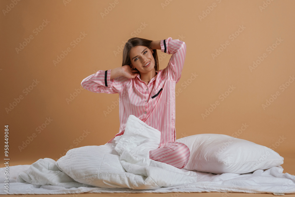 Front view, in pink pajama, waking up. Young pretty woman is against background in the studio Front view, in pink pajama, waking up. Young pretty woman is against background in the studio
