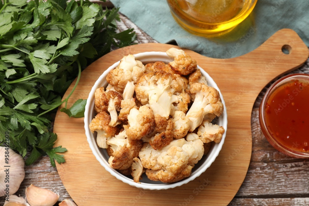 Baked cauliflower, sauce and products on wooden table, flat lay Baked cauliflower, sauce and products on wooden table, flat lay