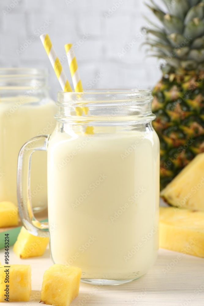 Tasty pineapple smoothie in mason jar and fresh fruit on white wooden table Tasty pineapple smoothie in mason jar and fresh fruit on white wooden table