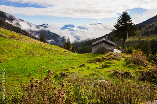 Lonely house in Austria mountains over cloudy sky. Natural landscape with cabin on countryside