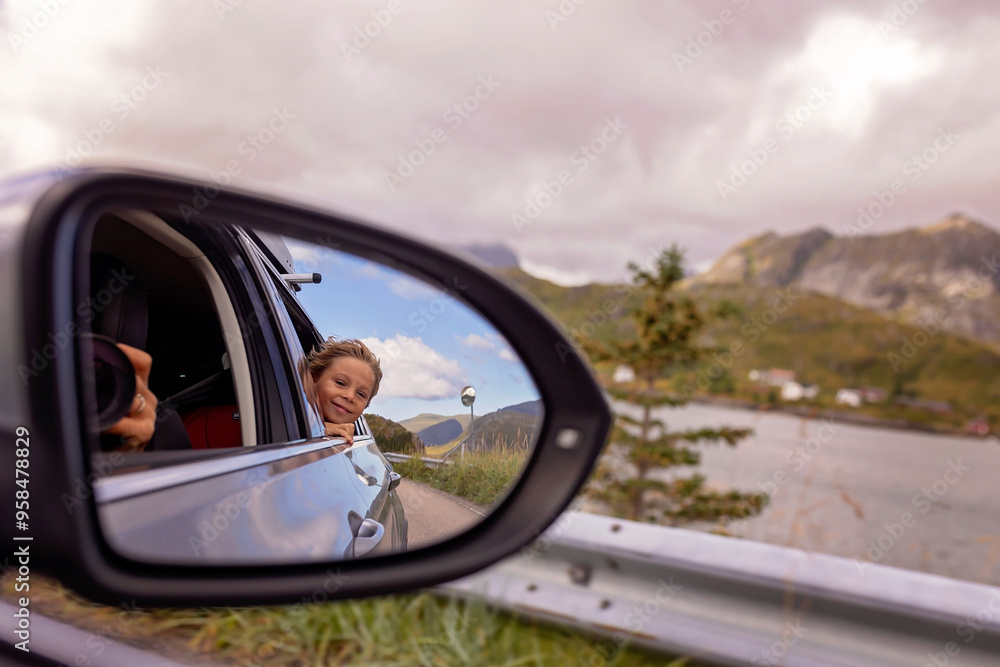 Cute blond child, looking out of the window of a car, reflection in the mirror Cute blond child, looking out of the window of a car, reflection in the mirror