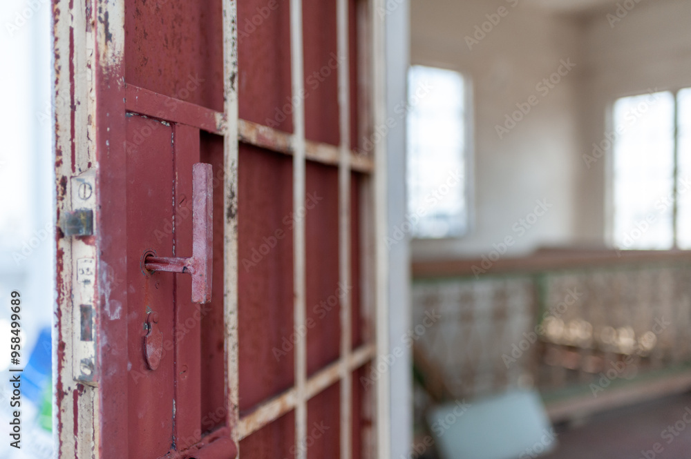 An old, weathered jail door slightly ajar, revealing an eerie interior filled with sunlight and abandoned furnishings. An old, weathered jail door slightly ajar, revealing an eerie interior filled with sunlight and abandoned furnishings.