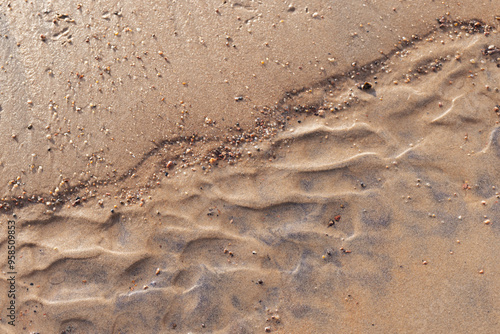 Wet sand ripples and peddle on the beach, top view. Abstract photo