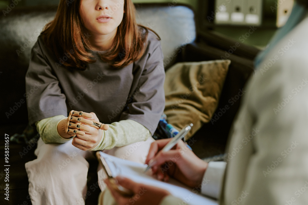 Fototapeta premium Young person engaging in therapy session with mental health professional in cozy office environment, showing attentive expressions and hand gestures while professional taking notes on clipboard
