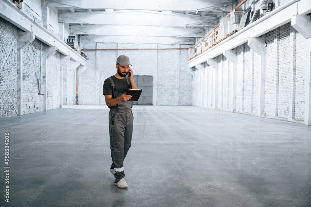 Business call, talking. Male worker is in the empty warehouse Business call, talking. Male worker is in the empty warehouse