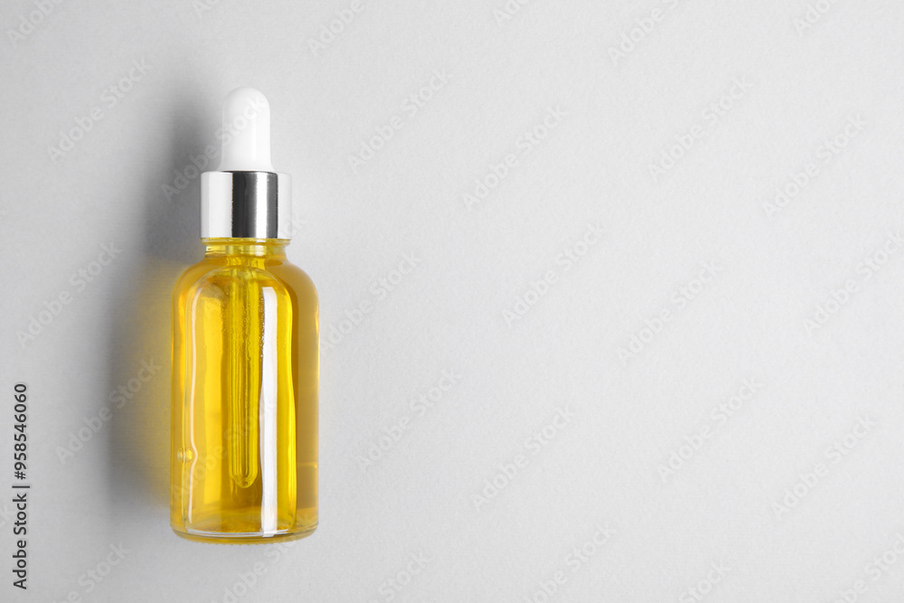 Essential oils in bottle on light background, top view. Space for text Essential oils in bottle on light background, top view. Space for text