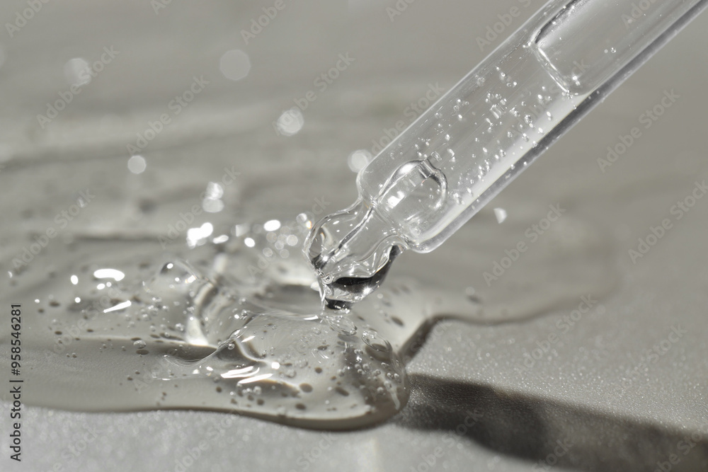 Dripping cosmetic serum from pipette on grey background, closeup Dripping cosmetic serum from pipette on grey background, closeup