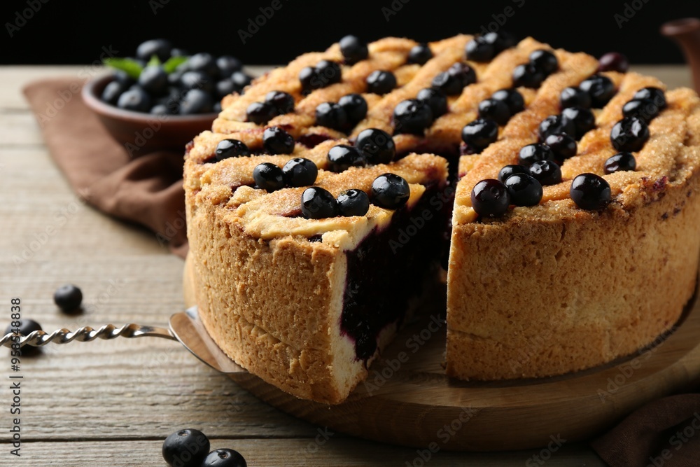 Taking slice of homemade blueberry pie and fresh berries on wooden table, closeup Taking slice of homemade blueberry pie and fresh berries on wooden table, closeup