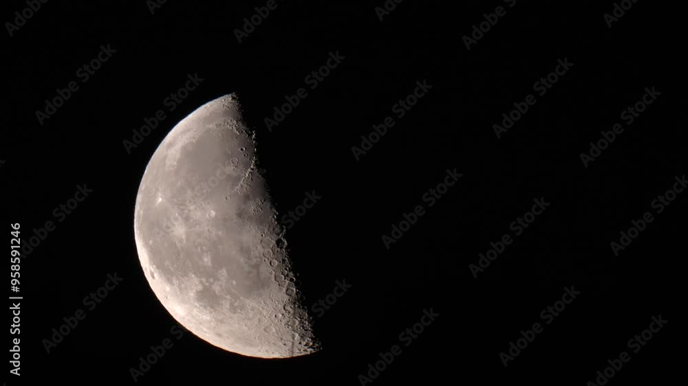 A half moon moving across the night sky, past a TV antenna foreground A half moon moving across the night sky, past a TV antenna foreground
