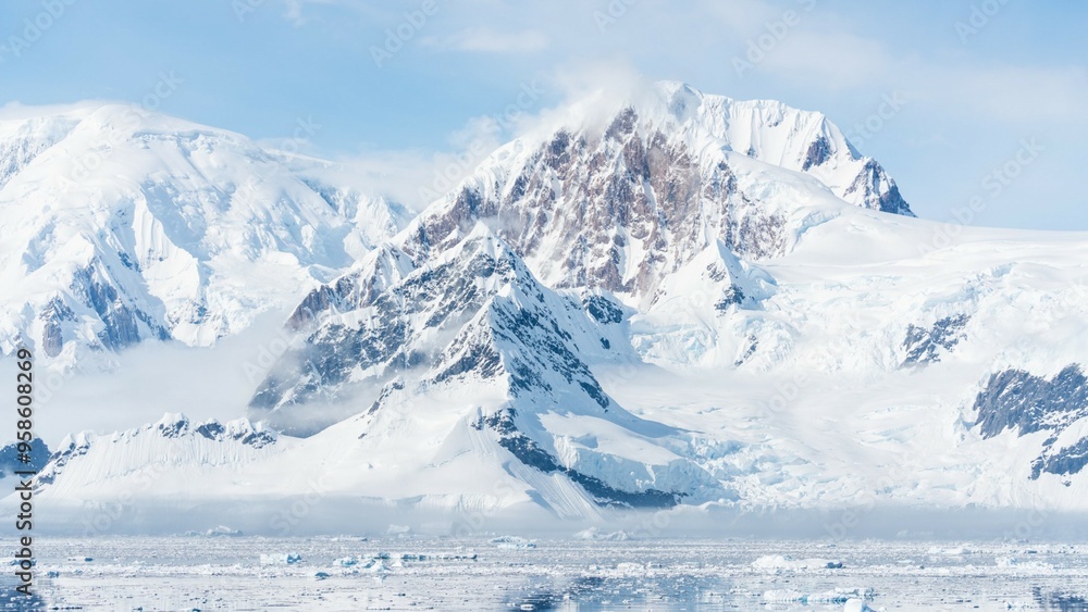 Obraz premium Majestic snow-covered mountains in Antarctica rise above the icy plains, creating a stunning frozen landscape
