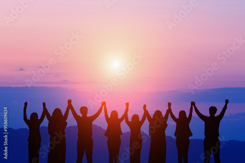 Silhouette of happy business teamwork making high hand over head standing in beautiful sunset  background for business success,.friendship,victory,cooperation,achievement,copy space.