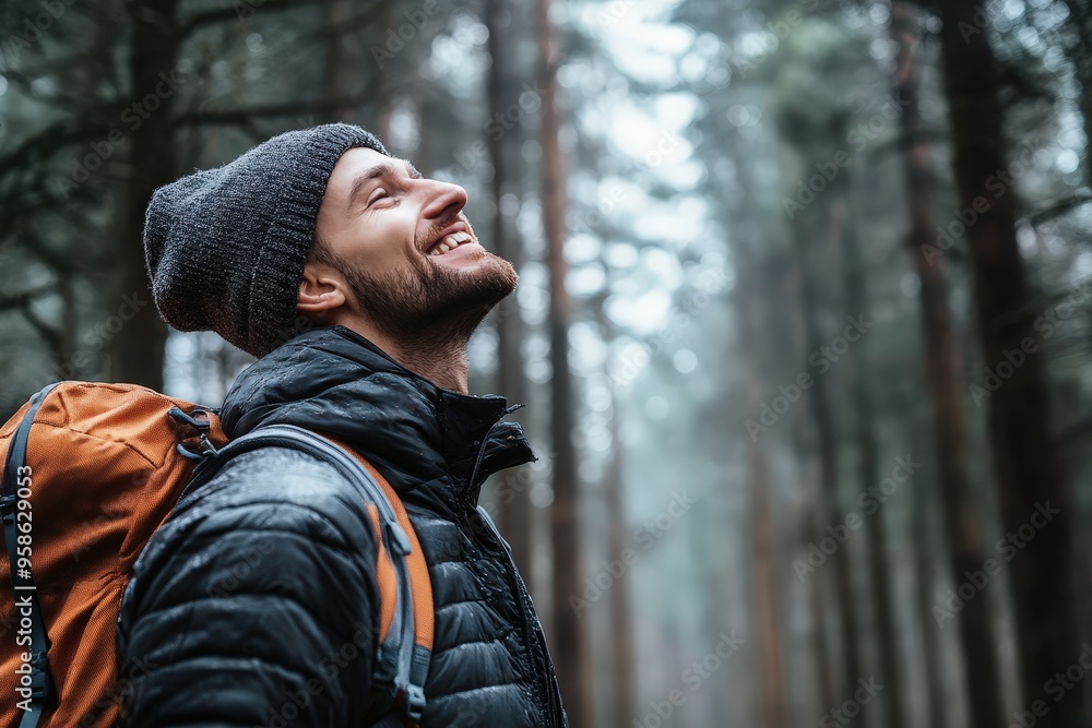 A hiker with an orange backpack, wearing a beanie and jacket, looks up while surrounded by a misty forest with tall trees, creating a serene natural ambiance. A hiker with an orange backpack, wearing a beanie and jacket, looks up while surrounded by a misty forest with tall trees, creating a serene natural ambiance.