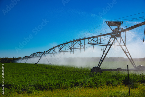 Foto Powered center pivot irrigation system in use to water large alfalfa field growing in central North Dakota