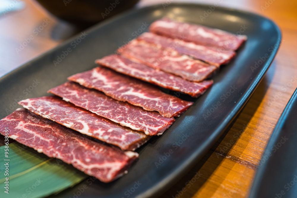 Premium fresh raw sliced Wagyu beef with marbled on black plate for grilled beef at Yakiniku restaurant background. A5 Yakiniku Wagyu beef sirloin served to Japanese barbecue grill, shabu or sukiyaki. Premium fresh raw sliced Wagyu beef with marbled on black plate for grilled beef at Yakiniku restaurant background. A5 Yakiniku Wagyu beef sirloin served to Japanese barbecue grill, shabu or sukiyaki.