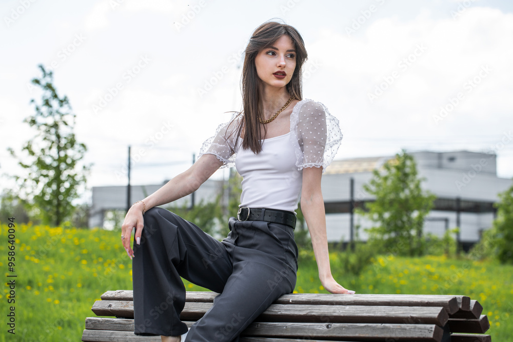 Young woman sitting on a bench in a summer park Young woman sitting on a bench in a summer park