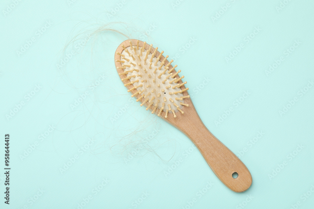 One brush with lost hair on light blue background, top view. Alopecia problem