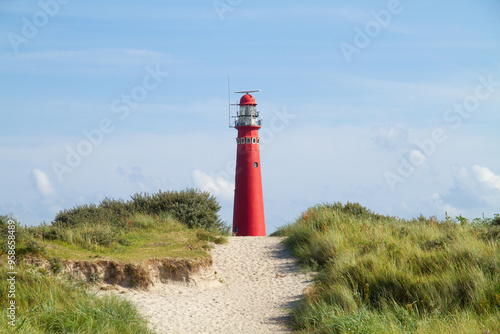 Path through the dunes to the red lighthouse of the Dutch island Schiermonnikoog