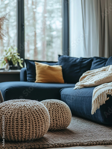 A living room with white walls. A modern Scandinavian interior living room photo with a blue sofa and beige knit poof. Generative AI