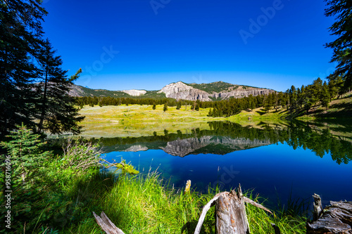 Yellowstone National Park's Trout Lake with beautiful reflections in the water and sun burst in the sky with mountains in the background