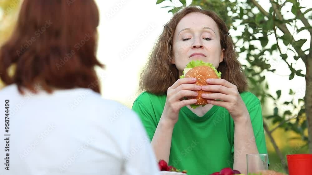 Woman eating a hamburger outdoors Woman eating a hamburger outdoors