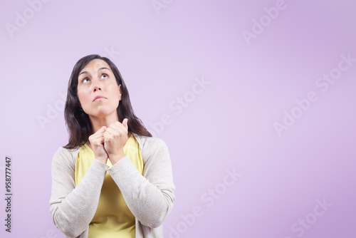 Woman isolated on lilac background looks up with fear and concern.