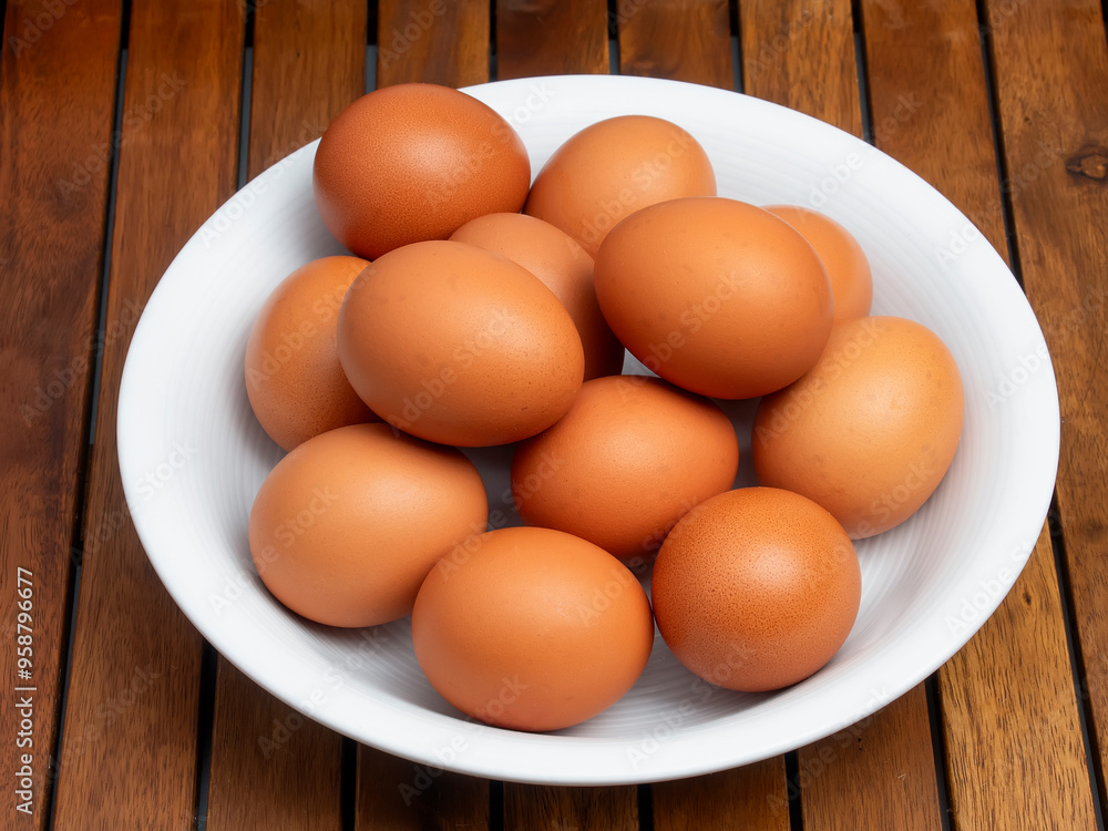 Huevos morenos de gallina en un bol sobre mesa de madera Huevos morenos de gallina en un bol sobre mesa de madera