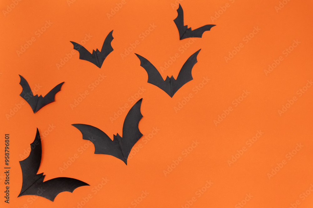 Fototapeta premium Halloween background - Black bats on bright orange background. Halloween atmosphere.