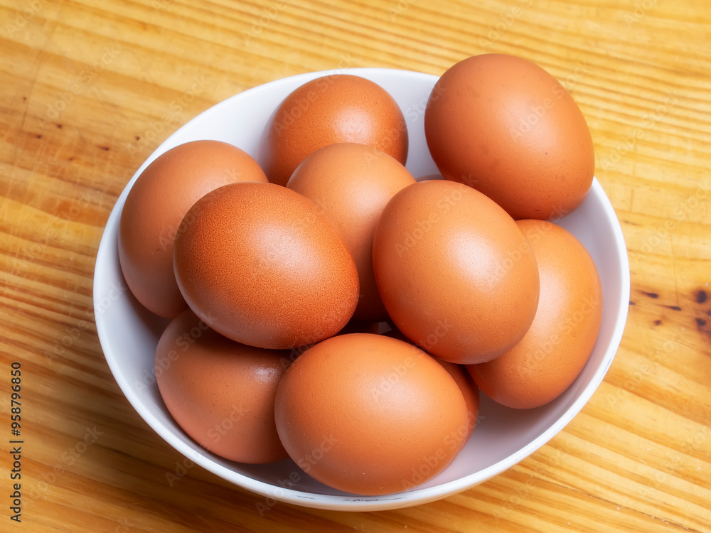 Huevos morenos de gallina en un bol sobre mesa de madera Huevos morenos de gallina en un bol sobre mesa de madera