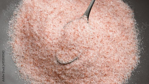 Crushed Himalayan pink mineral salt in a metal spoon. Fresh raw exotic culinary ingredient. Top view. Rotation