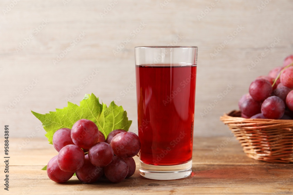 Tasty juice in glass, fresh grapes and leaf on wooden table Tasty juice in glass, fresh grapes and leaf on wooden table