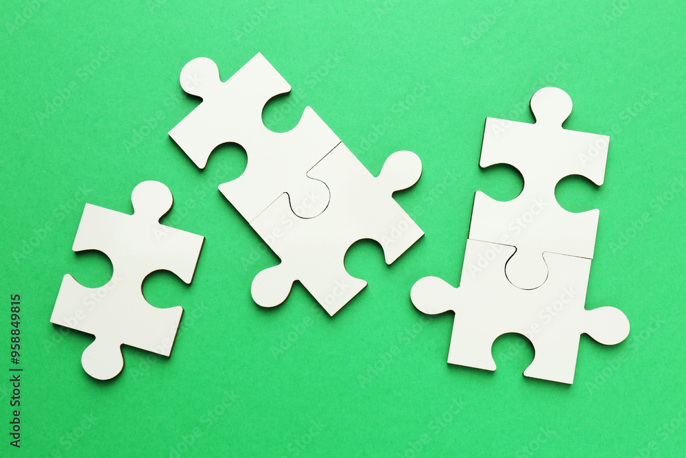 Obraz premium White puzzle pieces on green background, top view