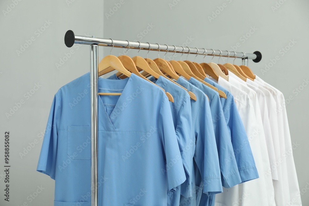 Obraz premium Different medical workers' uniforms on clothing rack against grey background