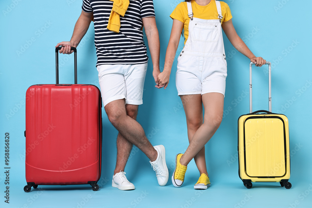 Woman and man with suitcases on light blue background, closeup Woman and man with suitcases on light blue background, closeup