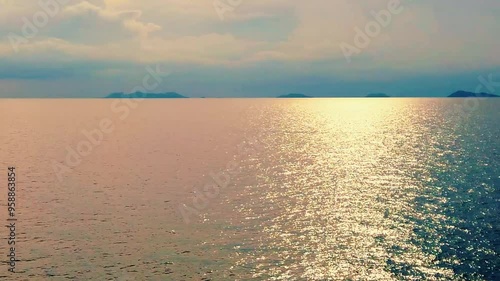 Golden Hour Sea: A serene and tranquil scene captures the breathtaking beauty of a golden hour sunset over a calm sea with distant islands, showcasing the shimmering reflection of sunlight on the wate photo