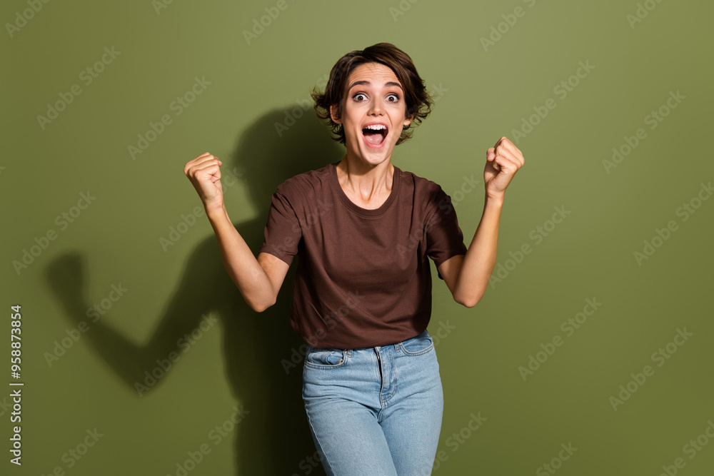 Fototapeta premium Portrait of overjoyed crazy girl with short hairdo wear oversize t-shirt scream yeah win betting isolated on green color background