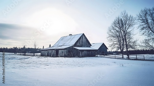 A rustic barn stands alone in a snowy field, with a line of trees in the distance.