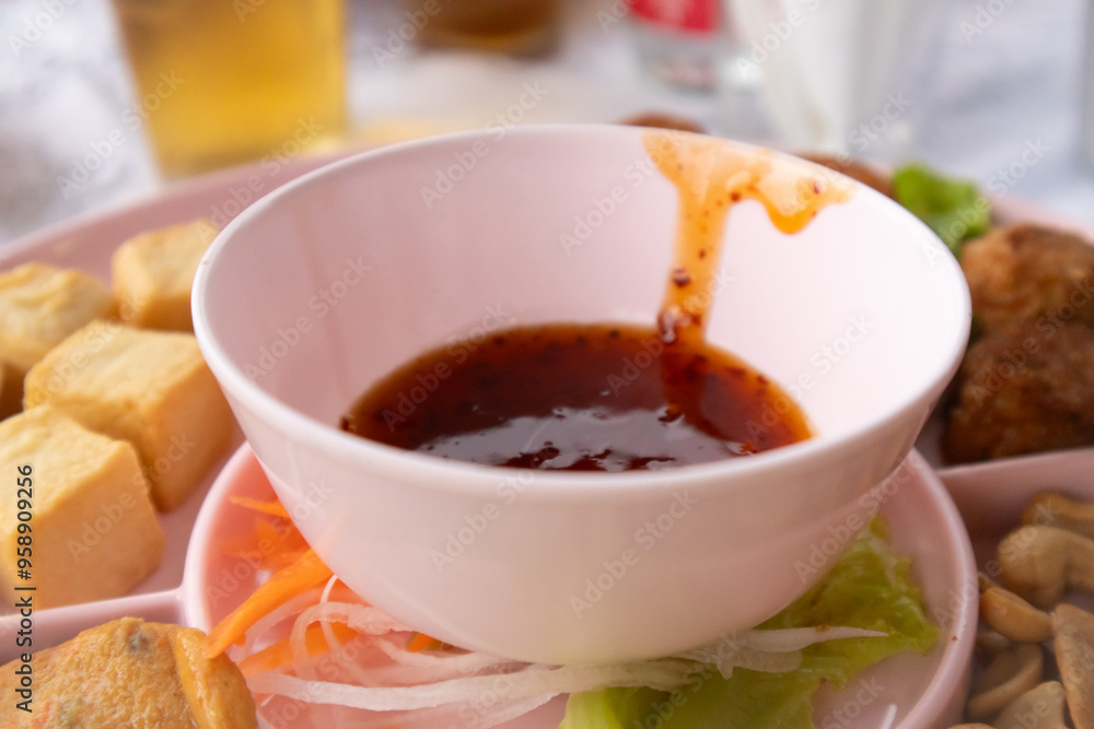 A cup of spicy dipping sauce has sauce smeared on the rim of the cup. A cup of spicy dipping sauce has sauce smeared on the rim of the cup.