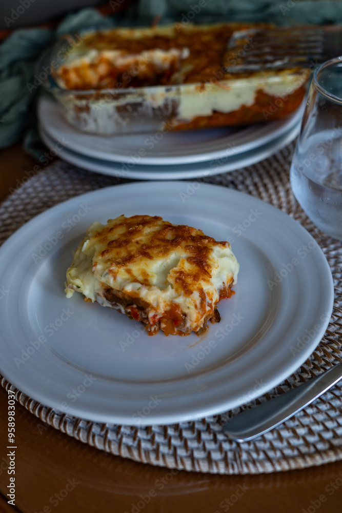 lasagna with tomato au gratin on a white plate at a table at home lasagna with tomato au gratin on a white plate at a table at home