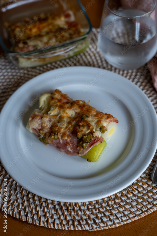 leek au gratin with cheese in the oven at a table at home leek au gratin with cheese in the oven at a table at home
