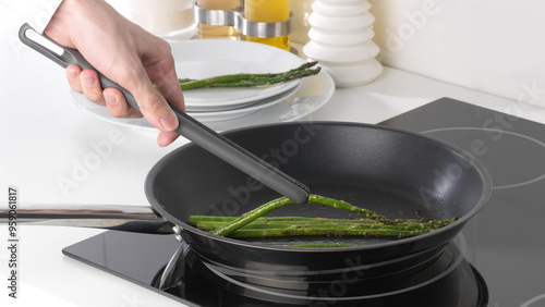 Closeup of a person flipping veggies in a frying pan with tongs. photo