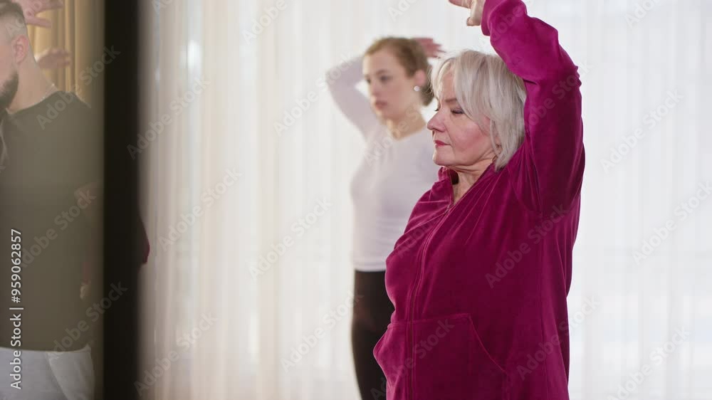 Senior Caucasian Woman of Practicing Standing Arm Stretch Exercise in Coordination in a Group Fitness Session. Concept of Active Aging, Motivation, Healthy Lifestyle, Training, Physical Activity Senior Caucasian Woman of Practicing Standing Arm Stretch Exercise in Coordination in a Group Fitness Session. Concept of Active Aging, Motivation, Healthy Lifestyle, Training, Physical Activity