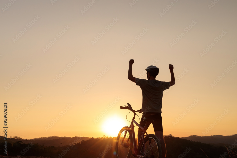 Mountain biker takes a break at sunset, raising an arm in celebration. The stunning sunset and peaceful atmosphere evoke a sense of achievement, freedom, and passion for outdoor adventure Mountain biker takes a break at sunset, raising an arm in celebration. The stunning sunset and peaceful atmosphere evoke a sense of achievement, freedom, and passion for outdoor adventure