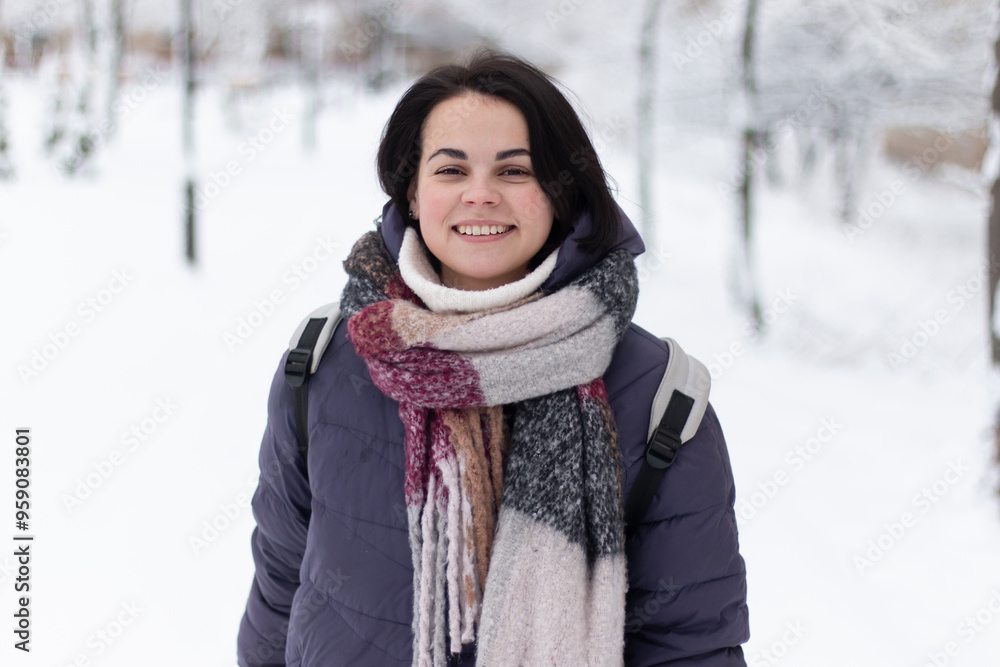 Young smiling beautiful woman wearing scarf outdoors during snowfall Young smiling beautiful woman wearing scarf outdoors during snowfall