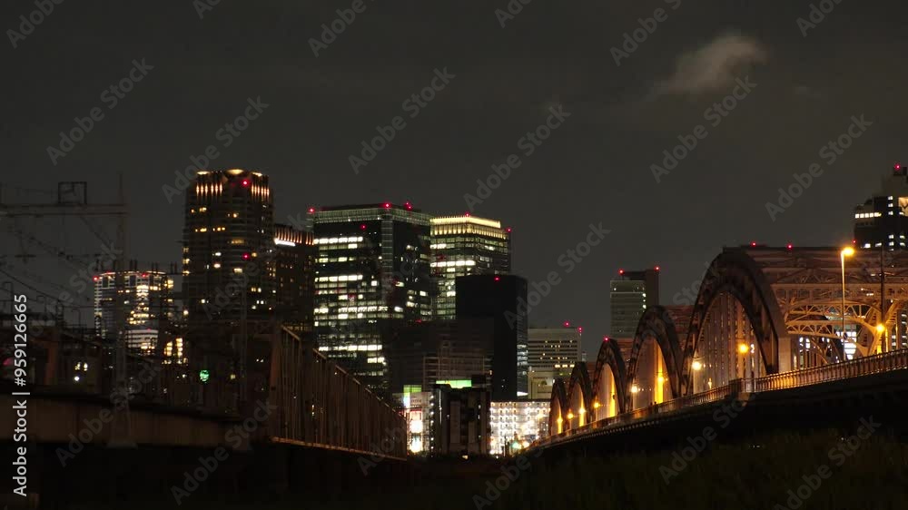 OSAKA, JAPAN - JUNE 2024 : View of train passing at Juso Ohashi bridge and buildings around Osaka station. Time lapse shot at night. OSAKA, JAPAN - JUNE 2024 : View of train passing at Juso Ohashi bridge and buildings around Osaka station. Time lapse shot at night.