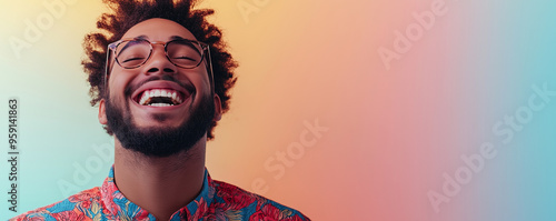 A man with glasses and a short beard, laughing heartily against a gradient background of pastel colors