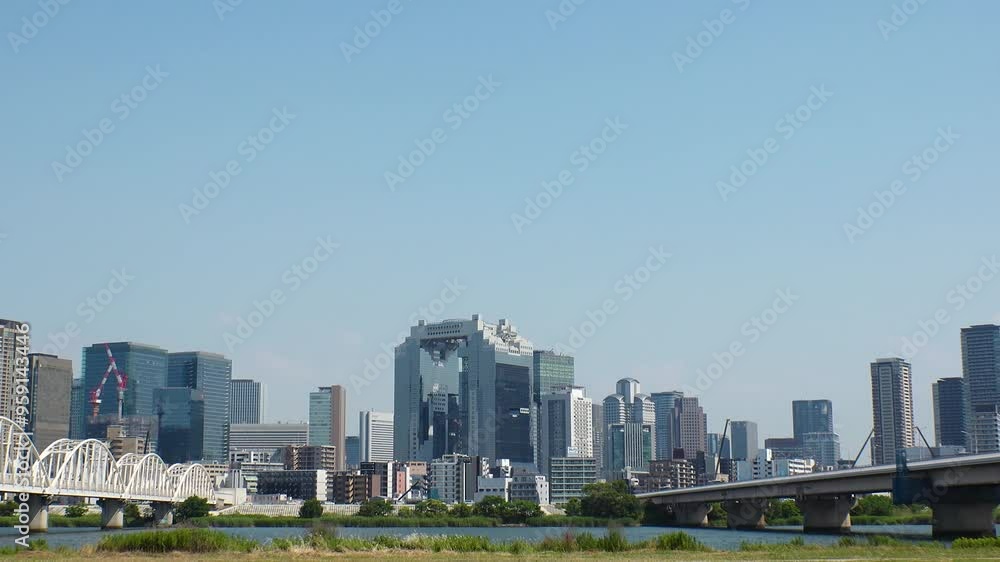 OSAKA, JAPAN - JUNE 2024 : View of buildings around Osaka station, bridge and Yodogawa river. Time lapse shot in sunny daytime. OSAKA, JAPAN - JUNE 2024 : View of buildings around Osaka station, bridge and Yodogawa river. Time lapse shot in sunny daytime.
