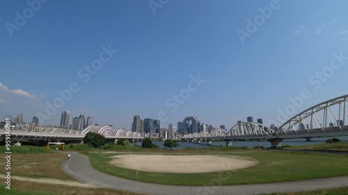 OSAKA, JAPAN - JUNE 2024 : View of buildings around Osaka station, bridge and Yodogawa river. Time lapse shot in sunny daytime. photo