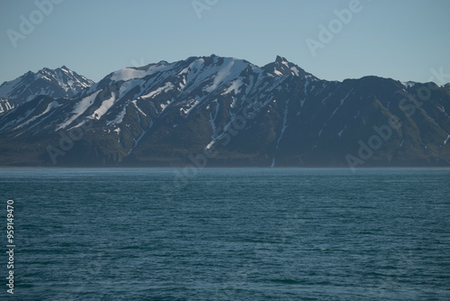 A bay surrounded by snow-capped mountains and dotted with ice formations. The magic of nature in its frozen splendor. A unique combination of ice and sea.Travel in cold weather, fresh air photo