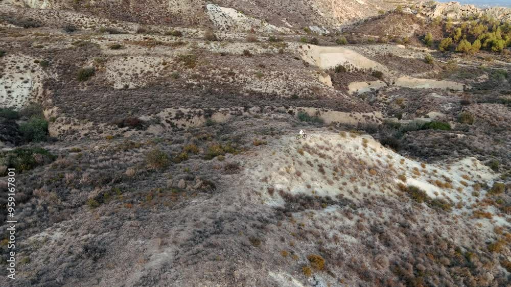 Aerial Flight. Drone cinematic shot Man Cyclist hiking alone in wilderness is approaching camera on a mountainside. Aerial view of beautiful mountain landscape Aerial Flight. Drone cinematic shot Man Cyclist hiking alone in wilderness is approaching camera on a mountainside. Aerial view of beautiful mountain landscape